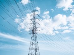 NGCP Restores Power to Five Central Philippine Islands A power transmission tower on a Philippine island with lights flickering on in the background after a blackout.